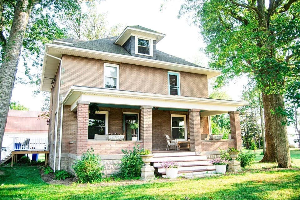 Charming front exterior of the house, featuring a cozy front porch with inviting seating, perfect for relaxing and enjoying the surrounding views.