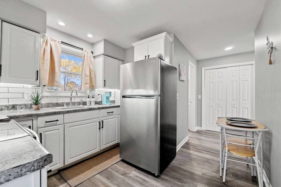 Compact kitchen with a fridge and a cozy dining area for two, perfect for intimate meals.