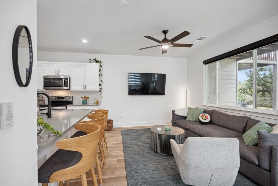 Open-Concept Living Space: A spacious, sunlit area with high-end furnishings and a smart TV for group entertainment. Enjoy the privacy shades at night.