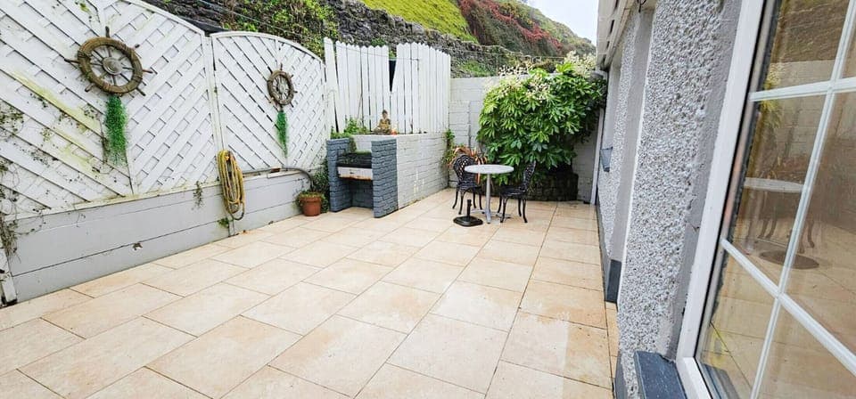 Passage East, Co Waterford. Family holiday home, close to ferry. Enclosed private back yard, clean bright paving slabs. Dining area. Foliage and garden ornaments.