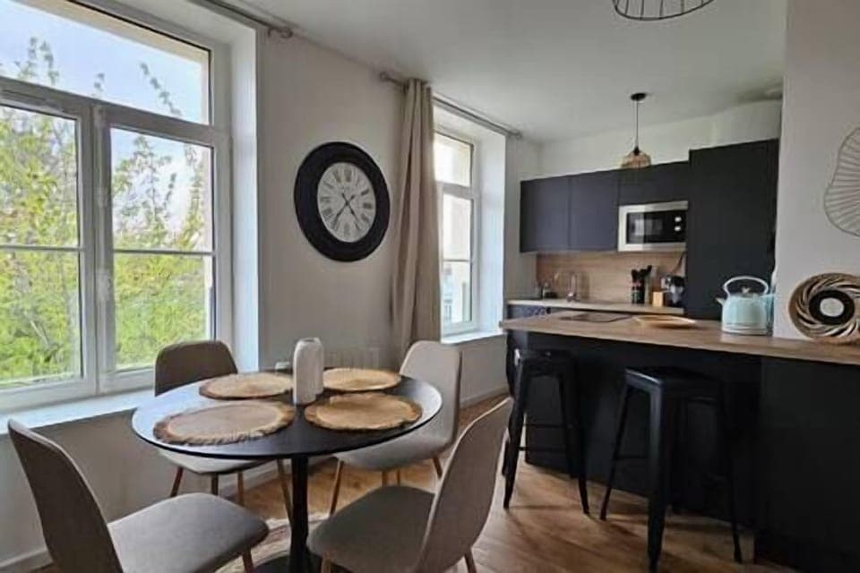 Espace salle-à-manger dans le salon, avec une table et quatre chaises, ouvert sur la cuisine. 