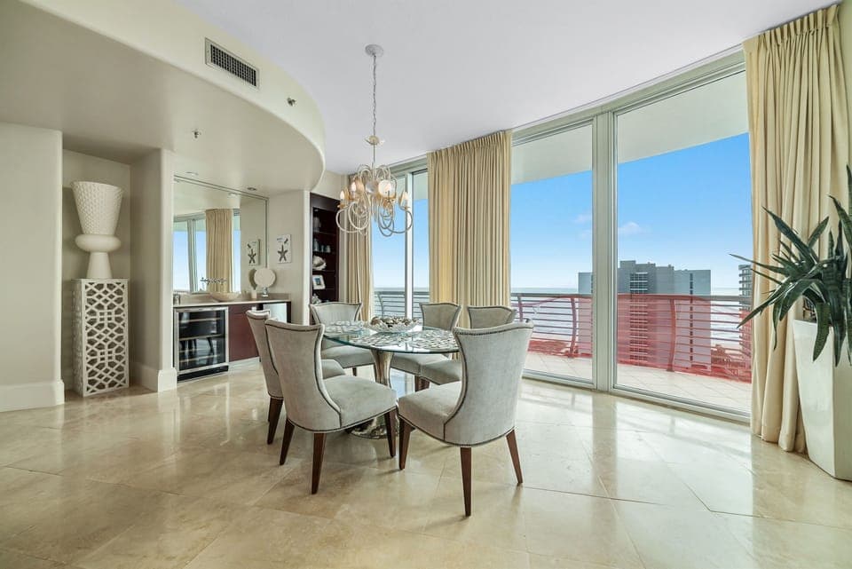 Sophisticated dining with panoramic coastal views. This exquisite 6-seater dining area is the centerpiece for formal entertaining, featuring premium stone flooring, custom cabinetry, and a captivating waterfront backdrop