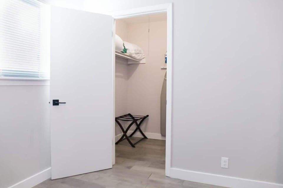 Full walk-in closet with iron, ironing board, clothes hangers, luggage rack