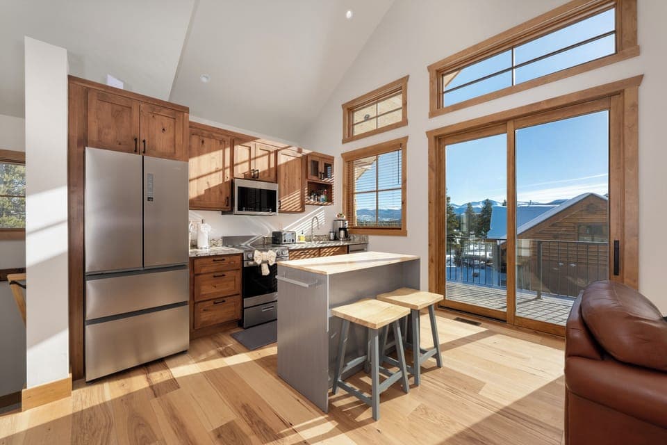 Sunlight streams through your floor-to-ceiling windows, illuminating this modern kitchen where you'll craft meals with mountain views as your backdrop.
