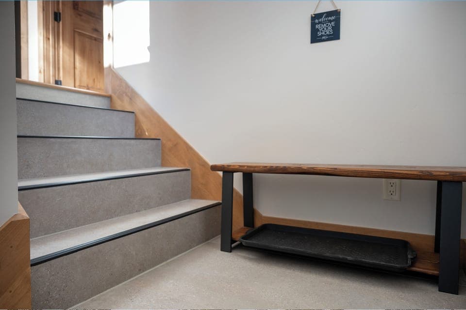 Step into your welcoming entryway where warm wood meets modern concrete stairs, complete with a thoughtful bench for removing shoes.