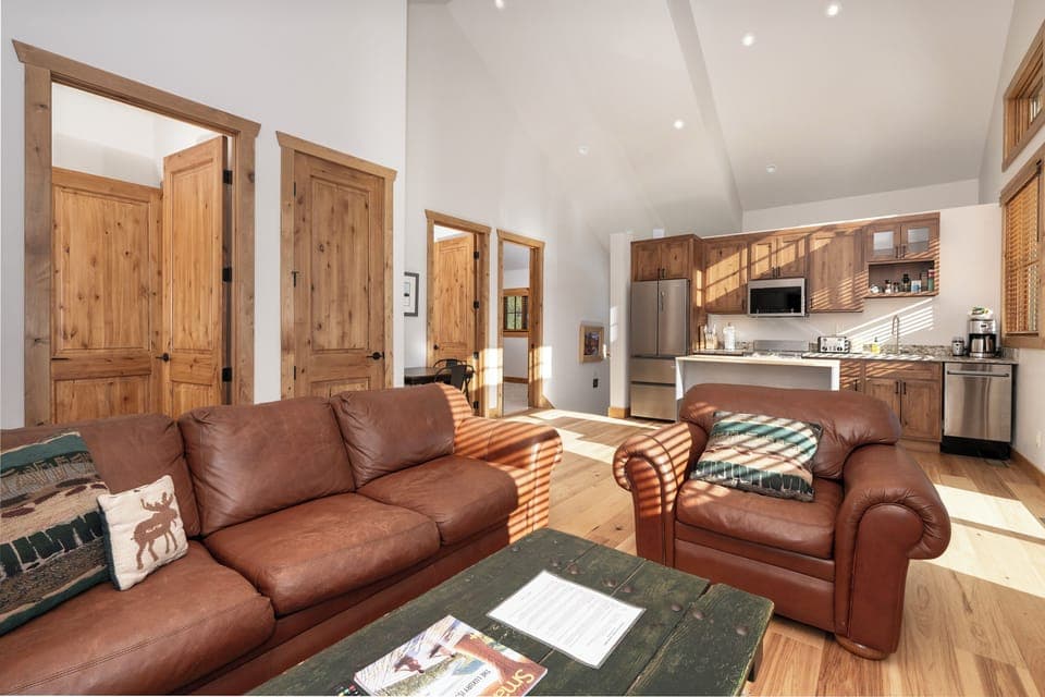 Relax on plush leather seating in your open-plan living space with warm wood details and modern kitchen.