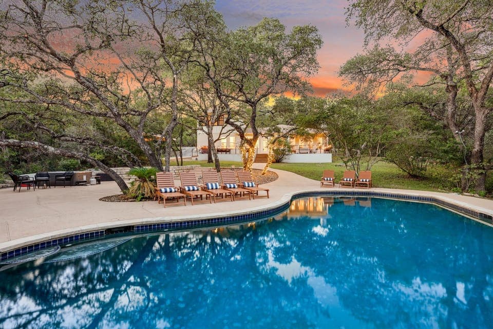 Set against a gorgeous sunset sky, this curved-edge pool is framed by trees and elegant loungers — a picture-perfect escape.