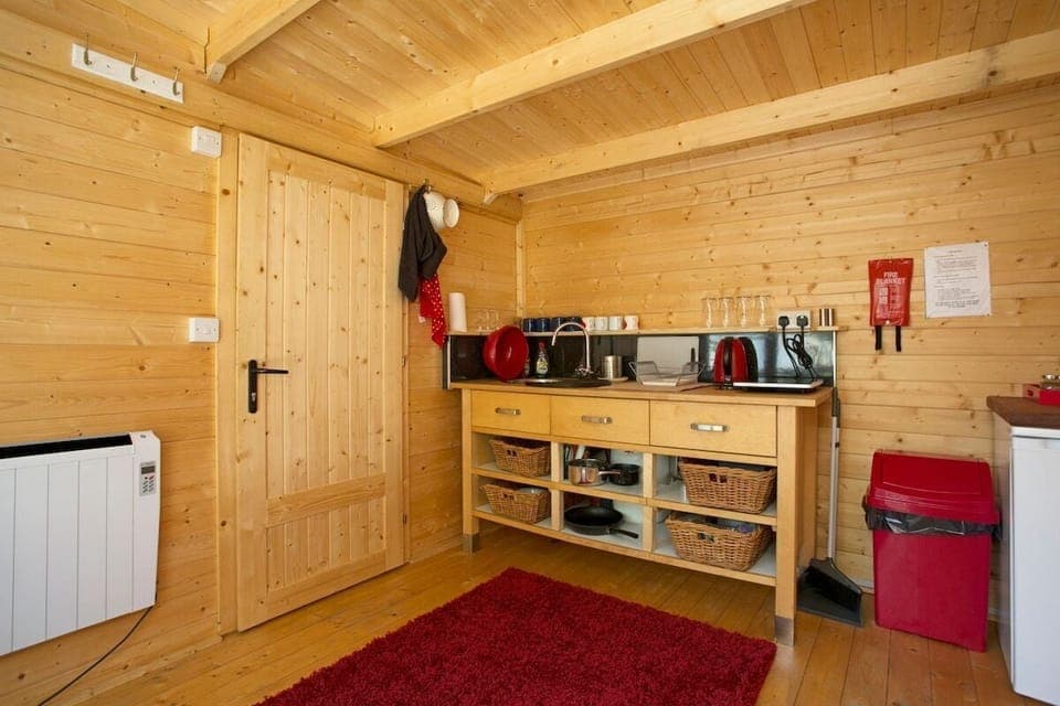 Kitchen area, with fridge, toaster kettle, hot plate and sink.