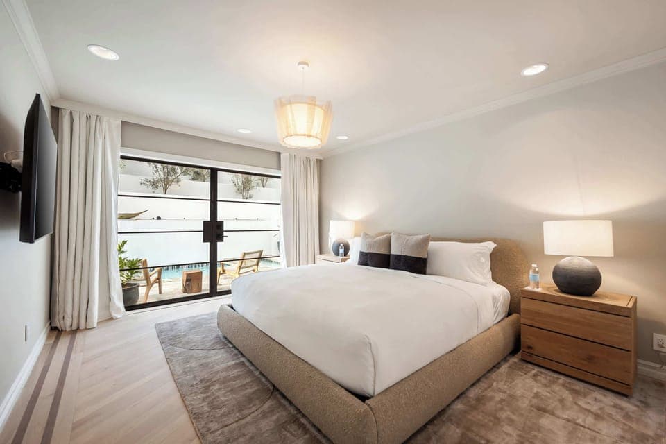 Bright and airy bedroom with crisp linens, layered textures, and serene garden views.