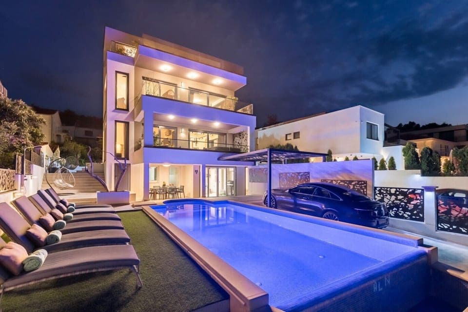 Night view of outdoor heated infinity pool and sun loungers in Luxury Villa Destiny Ciovo 1 with heated pool at the beach