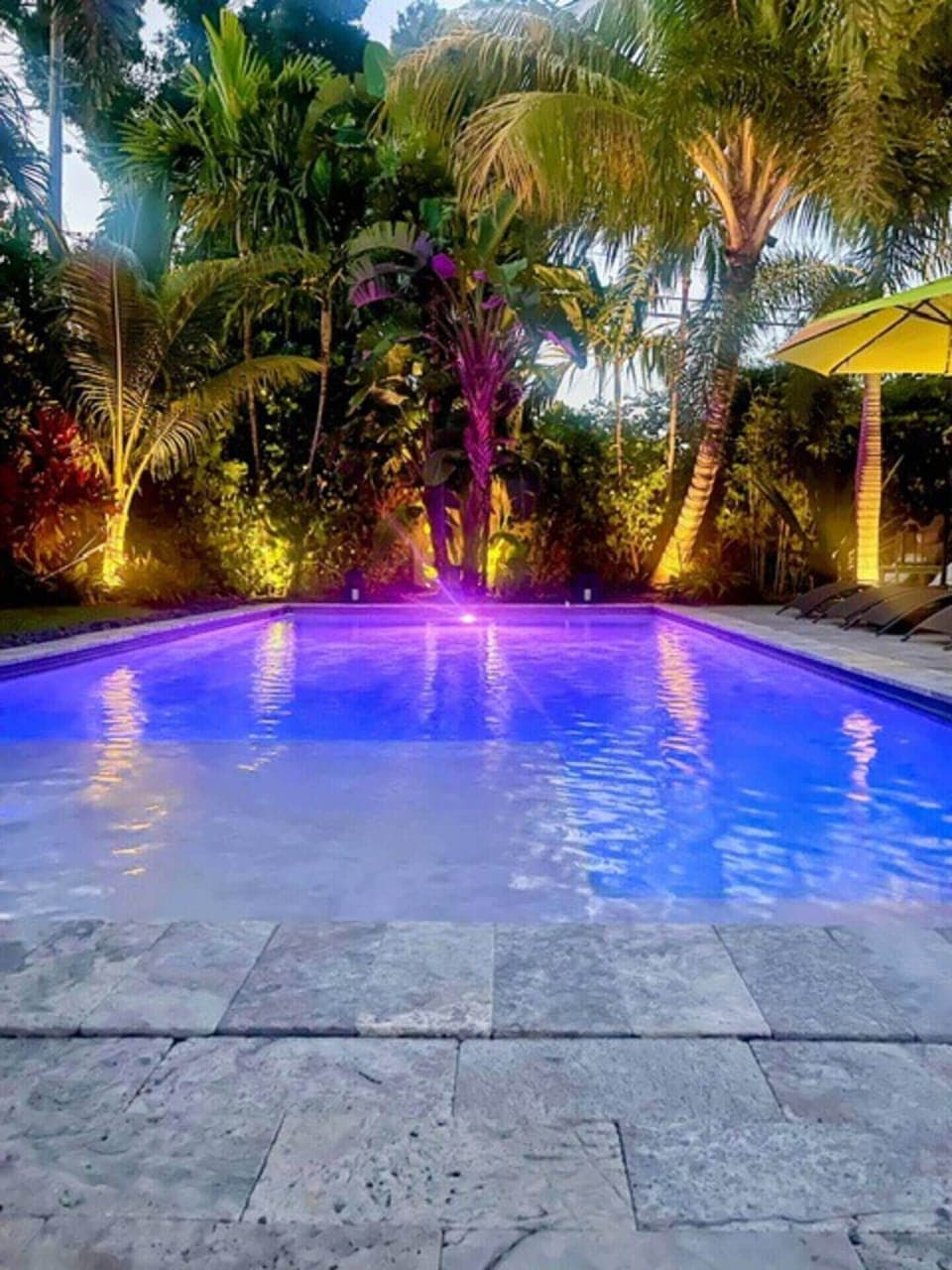 The backyard is a true oasis with a relaxing pool, lounge seating, outdoor dining and yard space, all surrounded by lush tropical landscaping