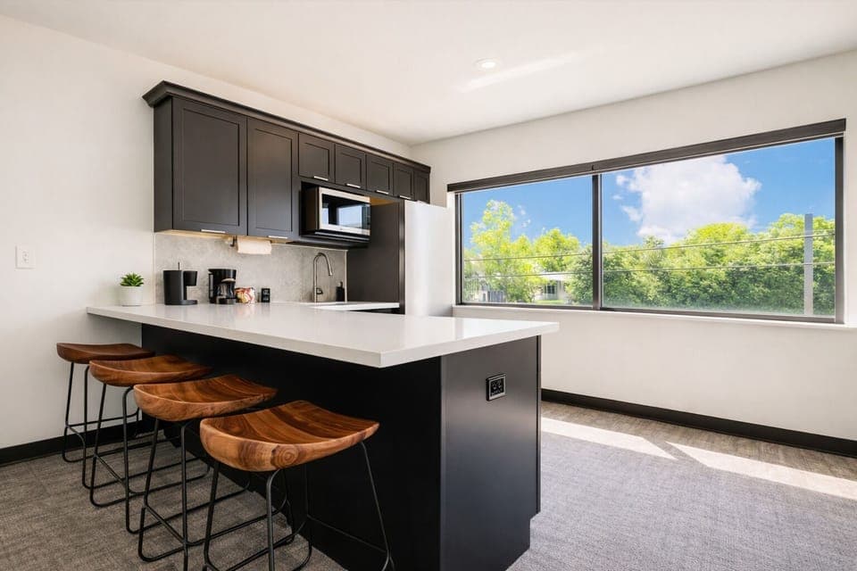 Enjoy the sleek, modern kitchen with a spacious island, elegant barstools, and large windows filling the space with natural light. Perfect for meals, drinks, or simply gathering with loved ones.


