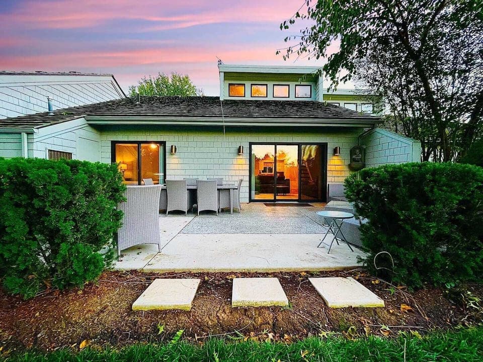 A serene backyard with a spacious patio, outdoor dining, and beautiful greenery, perfect for relaxing evenings.