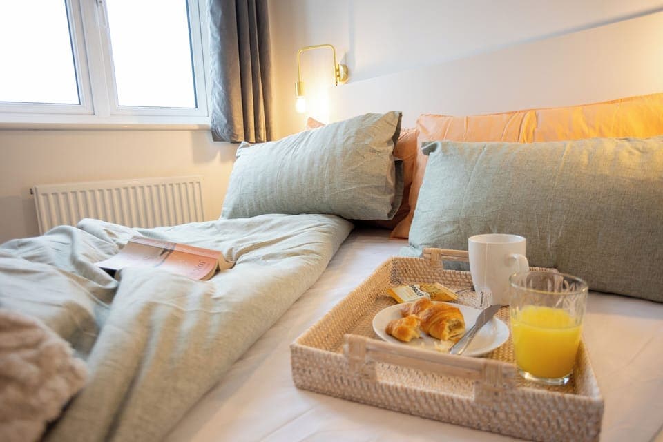 Cozy morning in bed. Window view of an open field. 