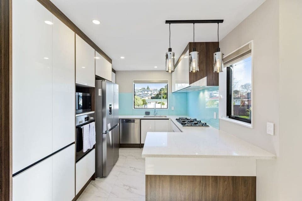 The kitchen is done in white with timber accents and has stainless steel appliances.