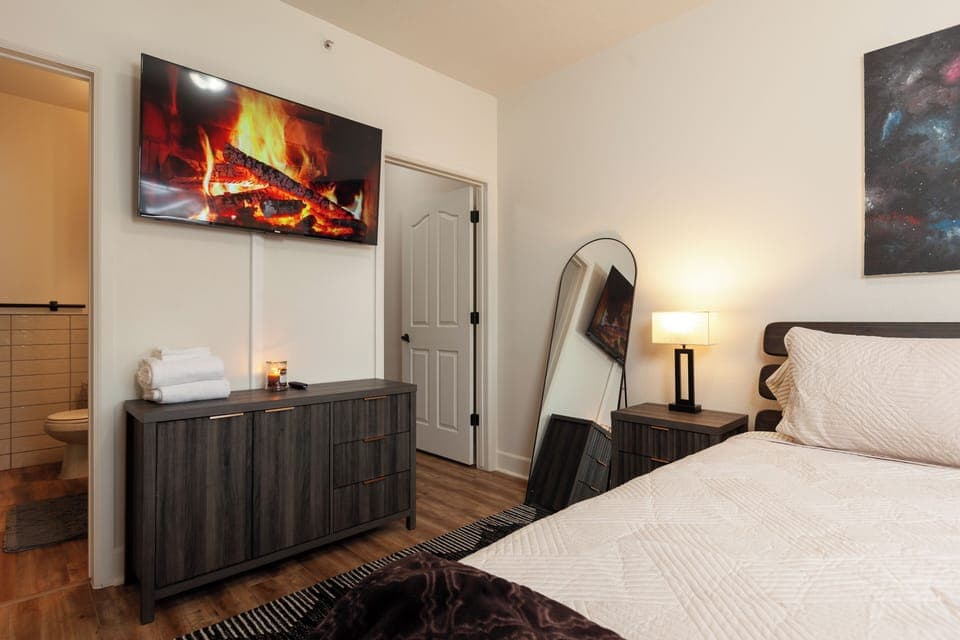 Primary Bedroom with TV, nightstands, full-length mirror, dresser, and access into the primary bathroom and walk-in closet. 