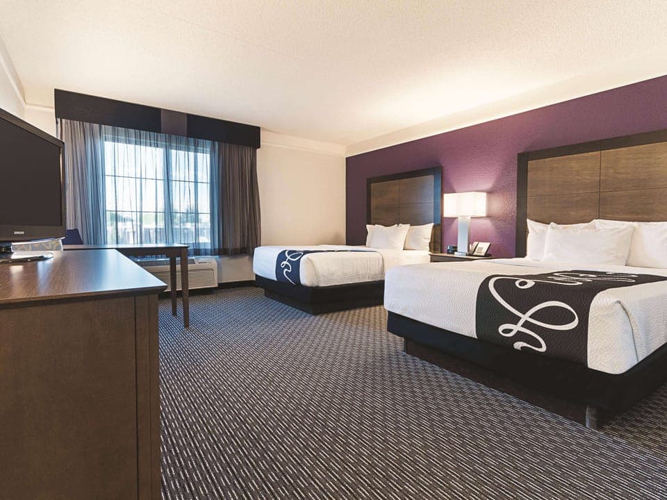 Unwind in a spacious double-queen room with bright window light.