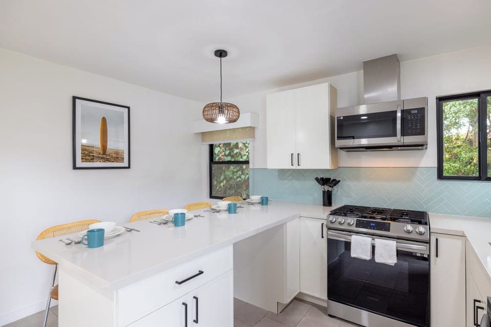 full kitchen with stove, oven, microwave, a bar with stools