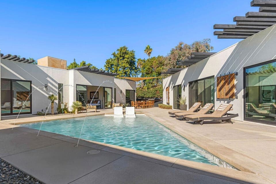 Sun-soaked pool w/ clean desert lines, lounge chairs, and swaying palms for laid-back afternoons under blue skies.