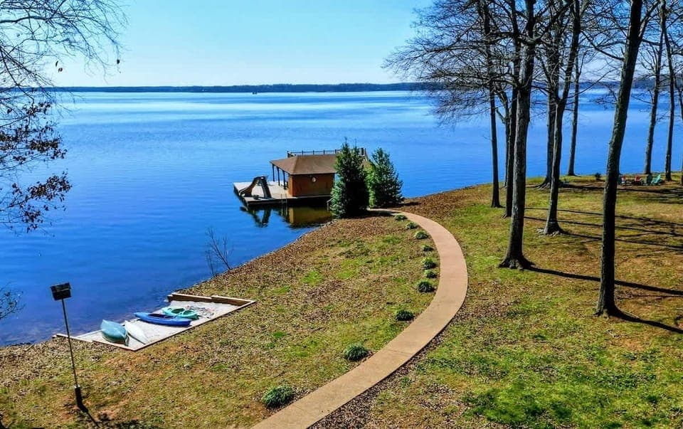 Scenic lakeside property with a winding path leading to a private boathouse and water slide, perfect for waterfront relaxation.