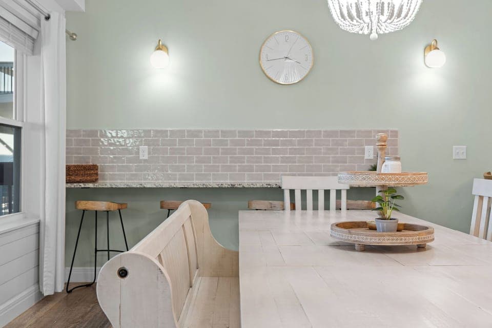 - Charming breakfast nook with a stone topped counter and rustic stools, perfect for coffee breaks
- Subway tile backsplash adds a touch of farmhouse chic and soft elegance
- Clock, sconces, and wall hues create a calm, modern country feel