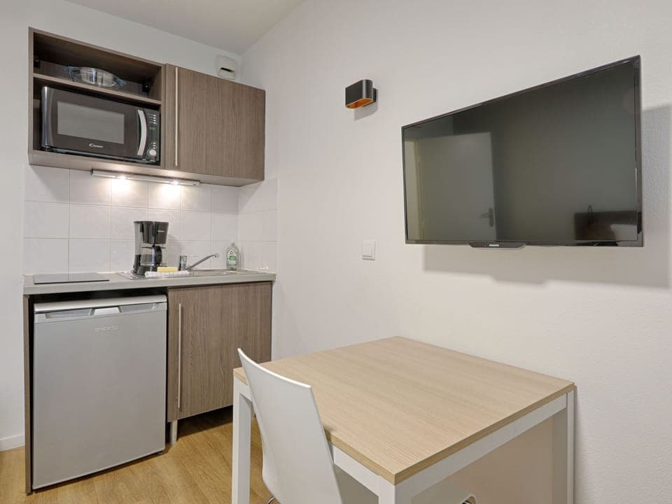  Fully equipped studio kitchenette with an electric hob, microwave, and compact dining area, perfect for independent travelers.