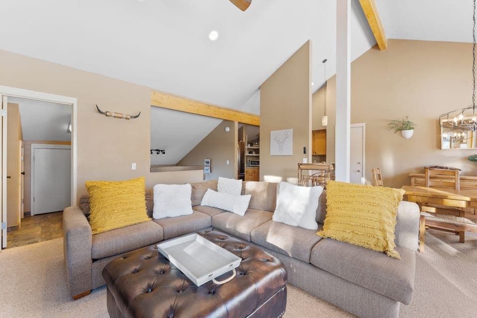 Living area with vaulted ceilings, flat-screen TV over a wood burning fireplace, double sized sleeper sofa, and balcony access.