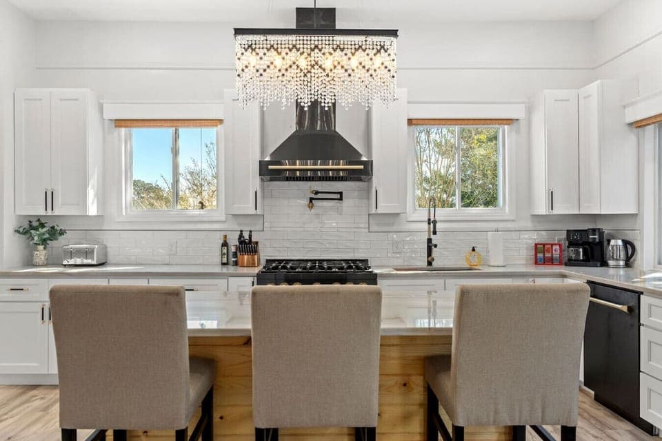 A lovely kitchen with an island that seats three, an exquisite chandelier, and windows that fill the space with natural light!