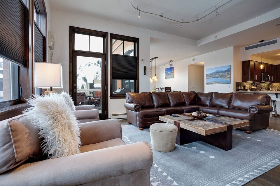 Sink into plush leather sofas by the warm fireplace, where mountain views frame your perfect retreat through expansive windows.