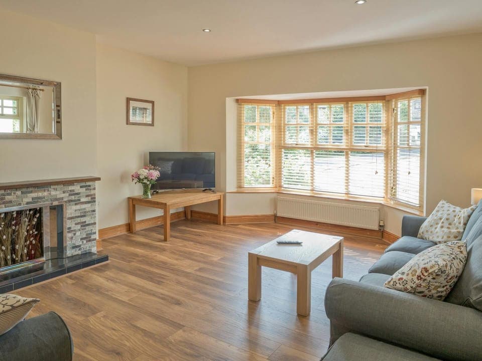 Coffee table, sofas, TV, blinds on the windows and flowers in a vase
