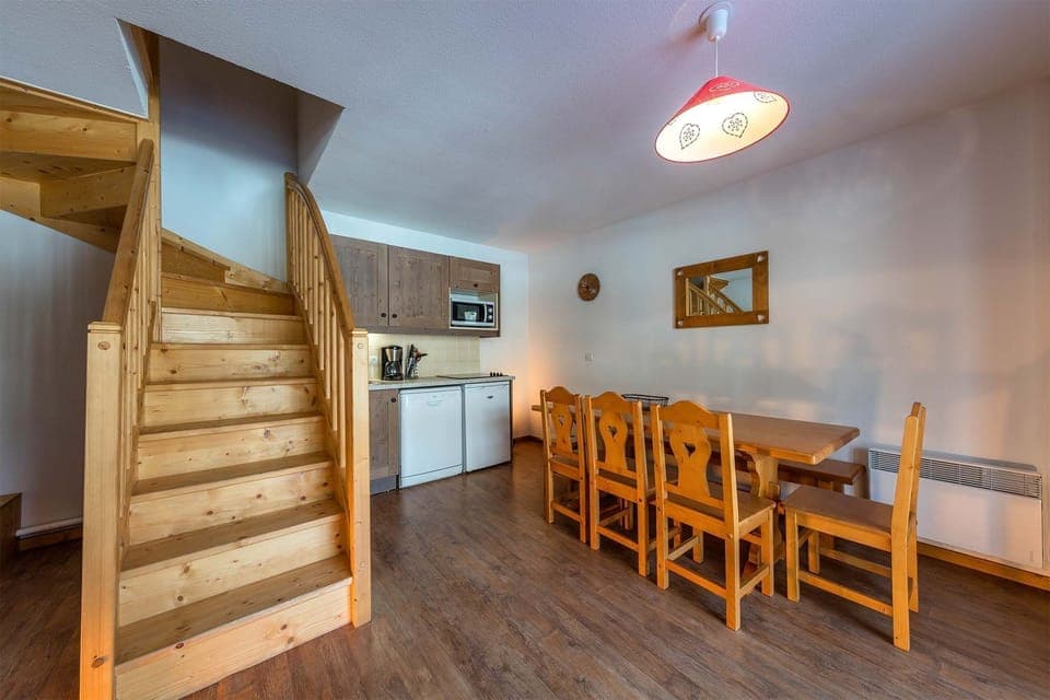 Spacious duplex apartment featuring a cozy dining area and a wooden staircase leading to the upper floor.