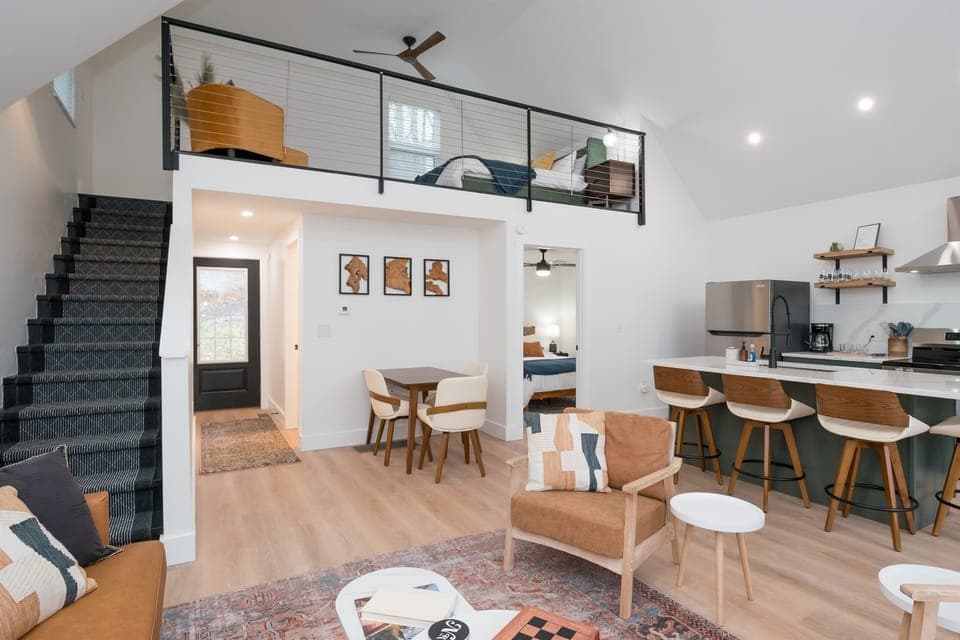 Bask in natural light and pond views from this stylish open-concept living area—featuring a fully equipped kitchen, cozy seating, and direct access to the outdoor deck.