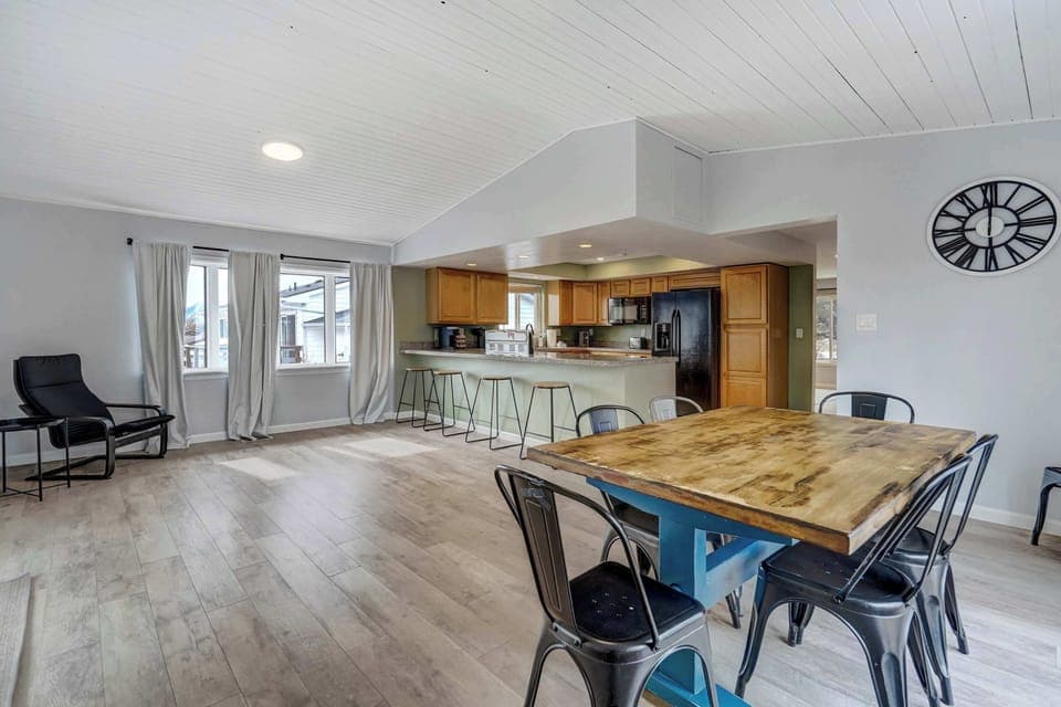 Spacious open-concept dining and kitchen area with a large wooden table, bar seating, and plenty of natural light—perfect for gathering and enjoying home-cooked meals.





