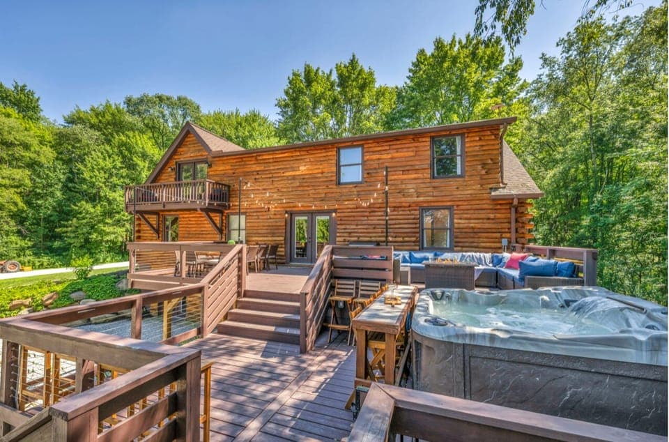 The spacious back deck, huge sectional sofa, outdoor dining, bar seating, and lots of flexible seating by the bubbling hot tub under the string lights.