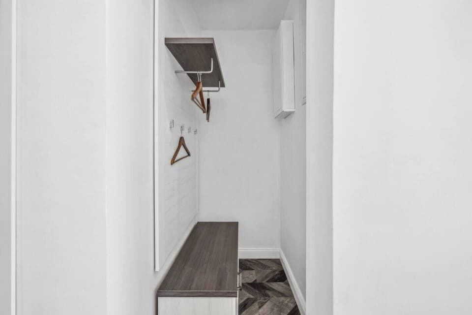 Praktischer Garderobenbereich mit Haken, Ablage, Kleiderbügeln und Sitzbank.