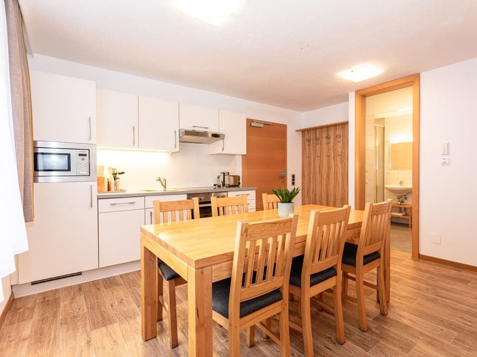 Dining room and kitchen in Appartements Hollin by we rent apartments in Saalbach, with a table, and chairs. Mountain view.