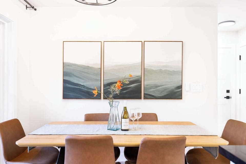 This cozy dining space is designed for gathering with loved ones. The warm wooden table, paired with elegant leather chairs, creates an inviting atmosphere. The large wall art behind the table adds a serene touchbringing a sense of calm to your meal.