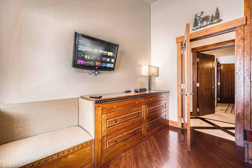Room with dresser, mounted TV, and soft lighting.