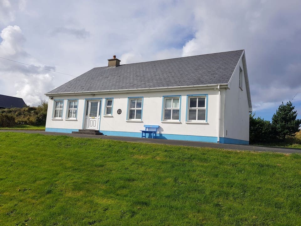 Front elevation of house, bench and huge garden.