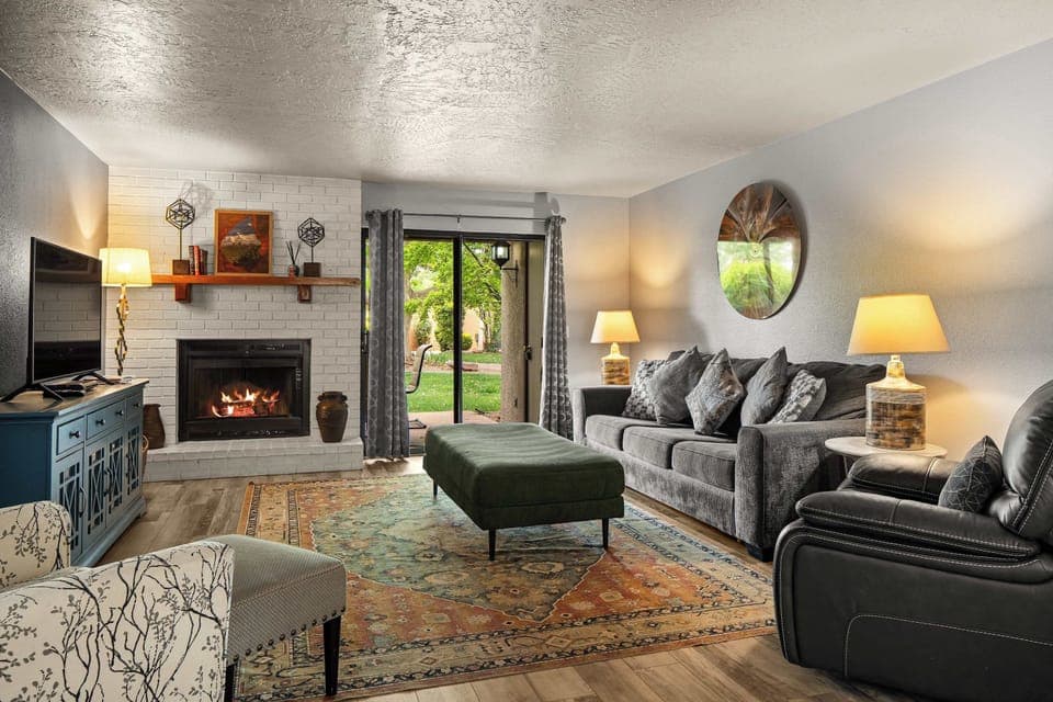 Cozy living room with fireplace, stylish seating, and backyard views through sliding doors.