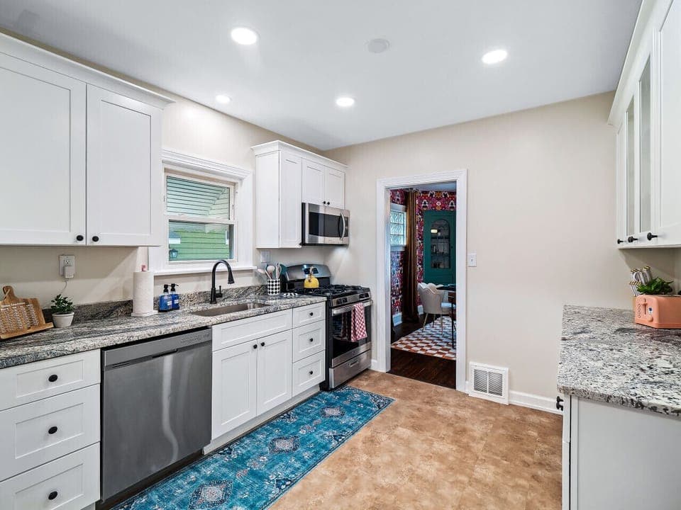 A bright and airy kitchen, perfect for cozy mornings and delicious dinners.  Sunshine streams in, illuminating the gleaming white cabinets and the vibrant rug. ✨ #homegoals