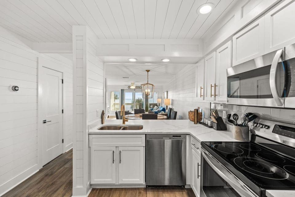 Your bright kitchen features crisp white cabinetry, stainless appliances, and quartz counters perfect for preparing meals while enjoying ocean glimpses.