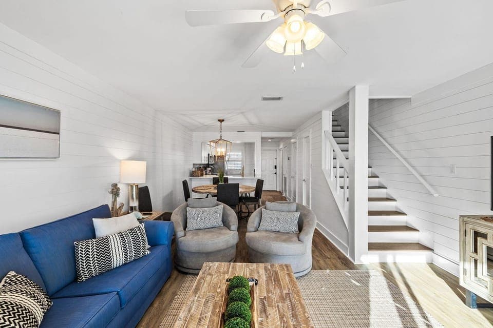 Relax in your stylish living space with coastal charm, featuring a cozy blue sofa and open layout perfect for gathering.