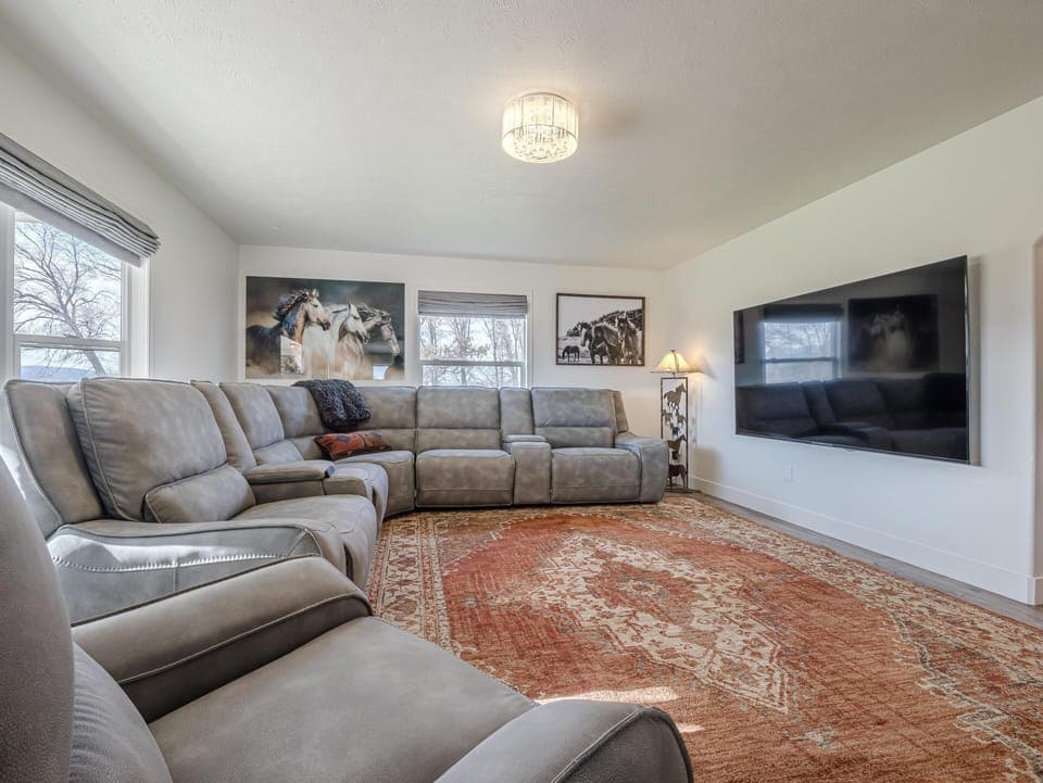 Gray leather sectional curves along two walls in the living room, anchored by a large patterned rug.
