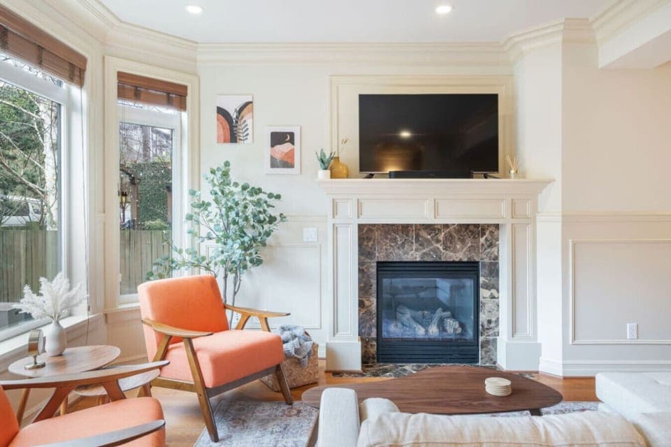 The living room has a marble fireplace, flat-screen TV, mid-century modern seating, and beautiful hardwood floors