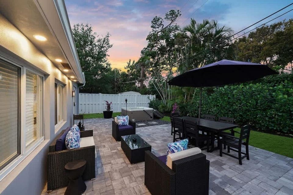 An inviting backyard with comfortable seating, a large dining table, and warm lighting.