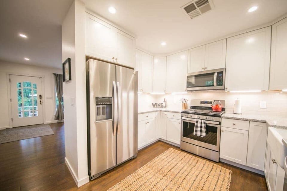 Newly renovated kitchen with gas stove, farm sink, and ice-dispenser.