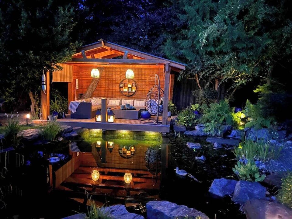 The dock at night with lights in the swim pond, and propane fire table.