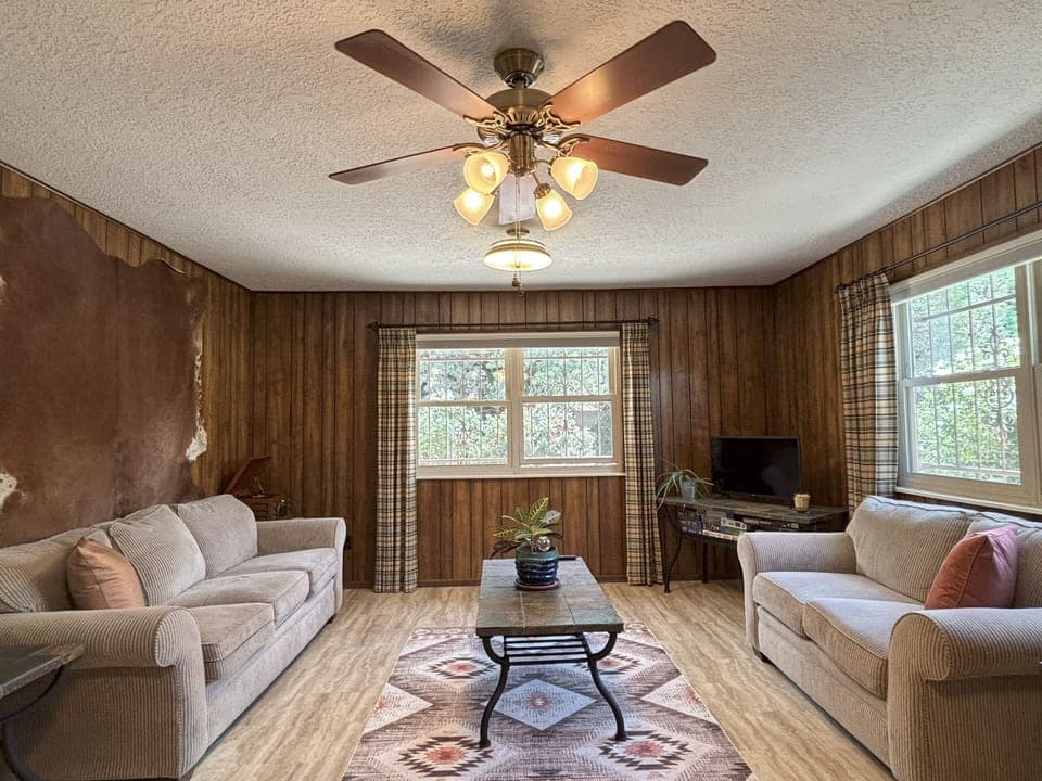 Cozy living room with warm wood panels and cute cabin like curtains. 