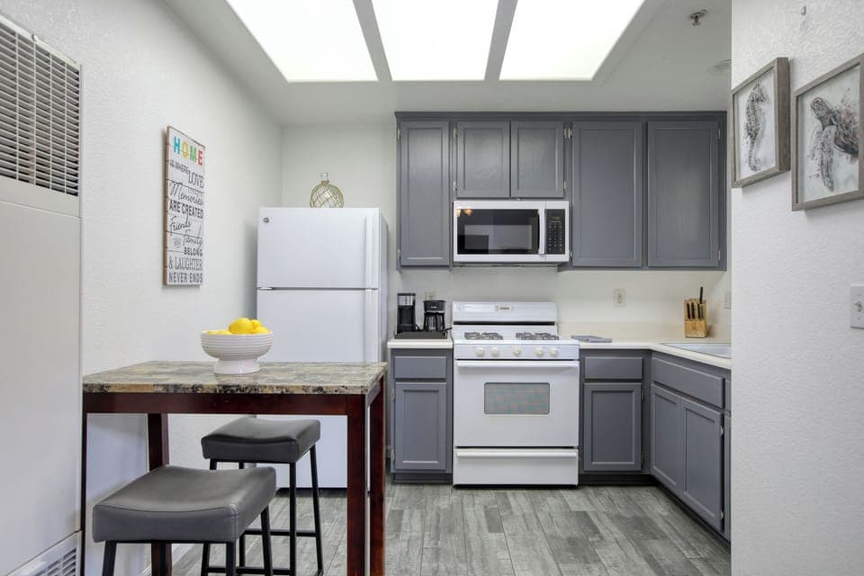 This modern kitchen features sleek gray cabinetry, full-size appliances, and a cozy dining nook for two.